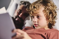 Man and boy reading together in bedroom