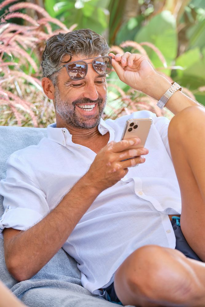 Cheerful man with sunglasses using smartphone