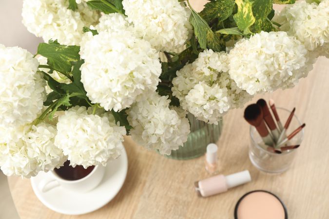 Composition with hydrangea flowers, cup of coffee and cosmetics. Spring plant