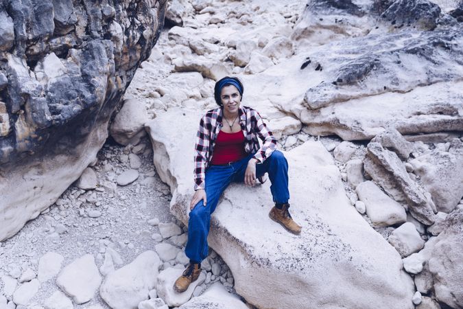 Positive woman sitting on stone