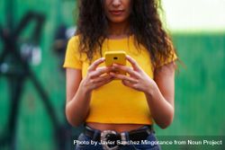 Cropped picture of woman in yellow t-shirt and jeans texting on phone 41Bwpb