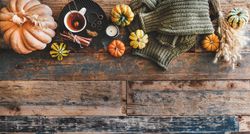 Flat-lay of dark green knitted sweater, and autumnal accessories, top view, copy space