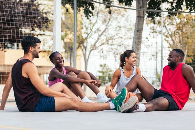 Friends sitting on the court talking after a basket game