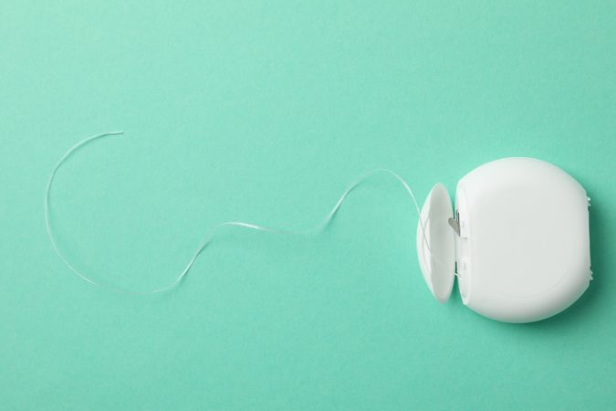 Tooth floss on mint background, space for text