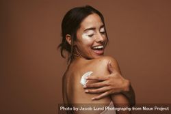 Side view of a woman with vitiligo and applying cream to her back 0Jkyd5