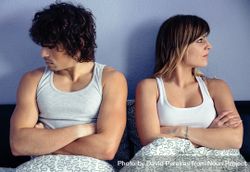 Angry couple sitting on bed with crossed arms 47meoO