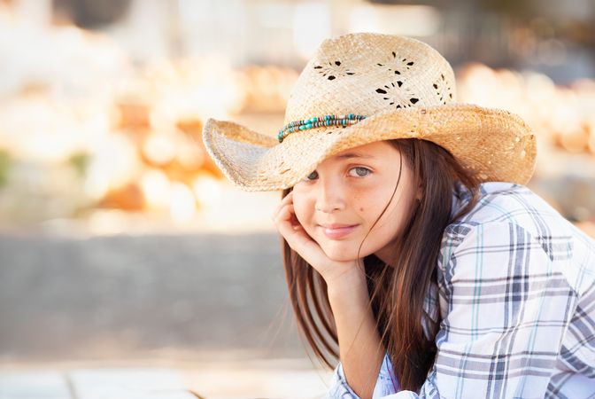 Girl Wearing Cowboy Hat Enjoying The Pumpkin Patch on a Sunny Fall Day.
