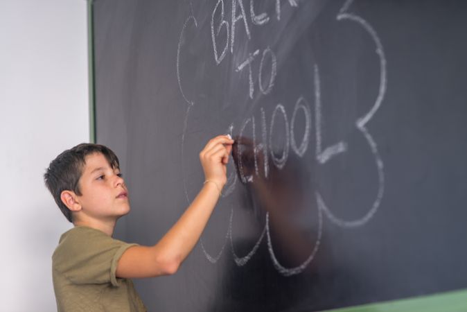 Boy writing "back to school" on chalkboard