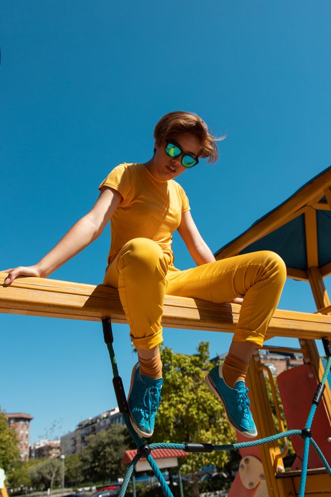 Cool stylish young woman in vibrant clothes on playground