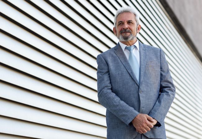 Portrait of a proud businessman standing next to lined wall