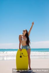 Happy woman standing at beach holding a bodyboard in front of her legs 5kE7Lb