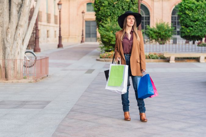 Content female in trendy wear doing shopping at city street
