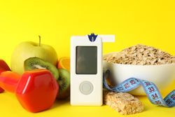Blood glucose meter and diabetic food on yellow background