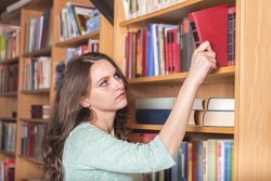 Woman picking a book from a library