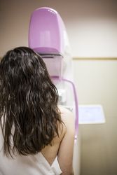 Female patient beside digital mammography unit