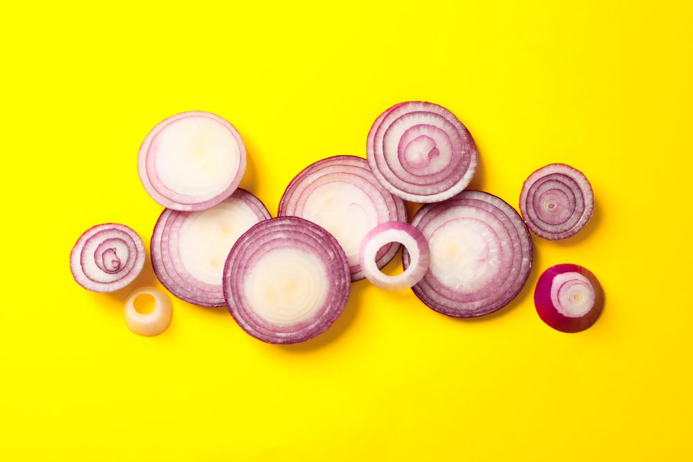Flat lay composition with red onion rings on color background