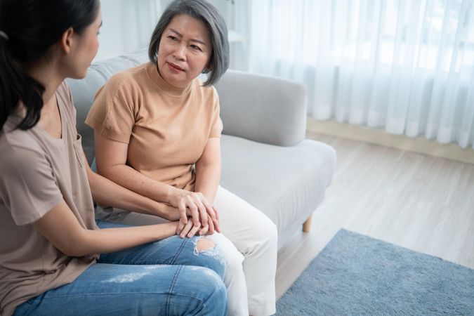Asian mature mother having compassionate conversation with her daughter, copy space
