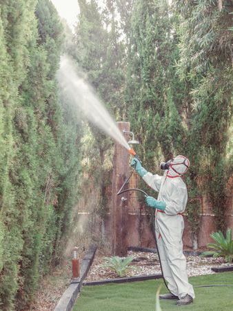Fumigator in uniform spraying substance on garden