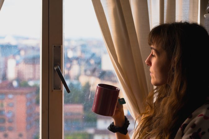 Woman enjoying hot beverage near fridge