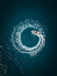 Aerial view of boat on water making spiral waves