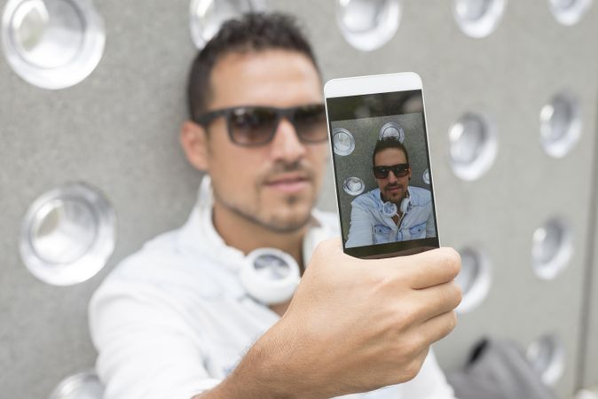 Phone screen of male in sunglasses taking picture outside