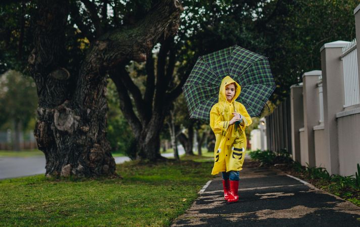 Girl wearing raincoat walking with umbrella
