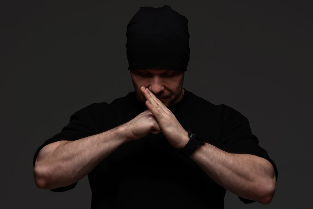 Man in beanie and sweatshirt pressing hands together
