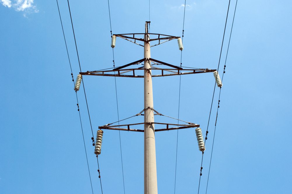 High Voltage Power Lines Against Clear Blue Sky