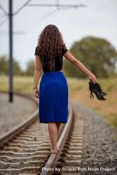 Woman walking on the train railings barefoot holding her heels 4Z3QOb