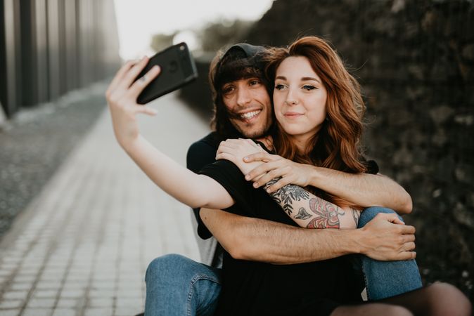Skaters sitting on road and taking selfie on smartphone