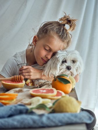 Little boy hugging dog and holding bottle of homemade lemonade