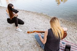 Young woman shooting friend playing guitar