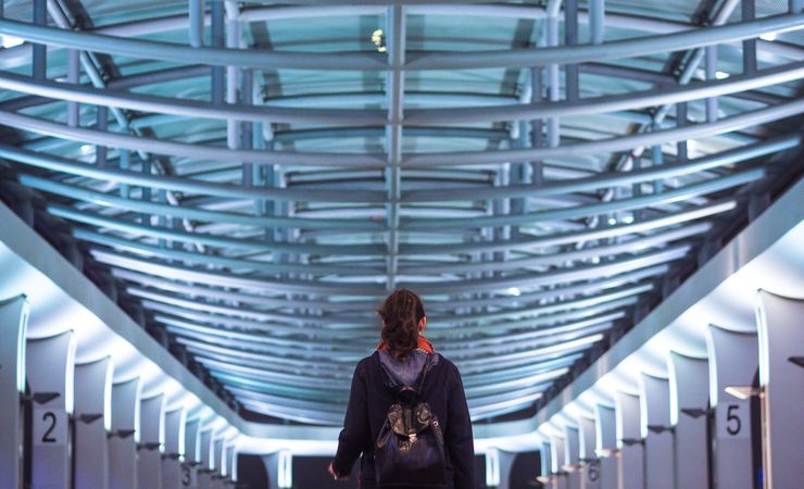 Back view of woman with backpack standing inside of a building