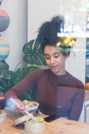 Black woman eating poke in restaurant