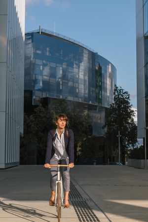 Cheerful businesswoman riding bicycle on street