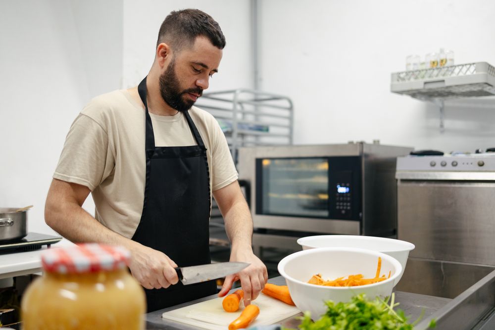 Young chef cutting carrots