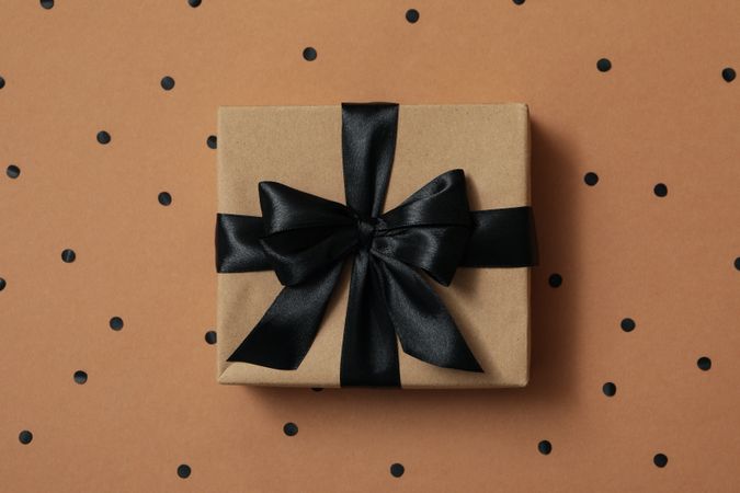 Gift box with dark bow on craft background