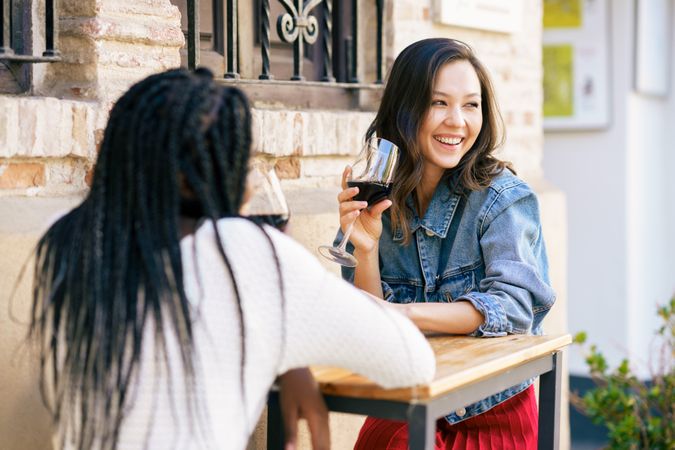 Female friends sipping red wine at an outdoor table at a restaurant