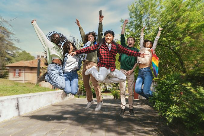 Multi-ethnic friends jumping joyously around campus