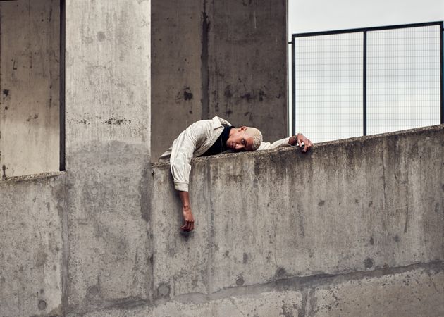 Young man slouching over cement wall