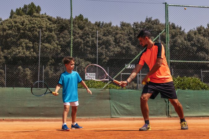Man coaching a boy in tennis