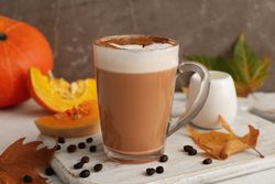 Composition with glass cup of pumpkin latte on light background