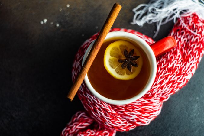 Top view of mug of hot wintry drink wrapped in red woolen scarf