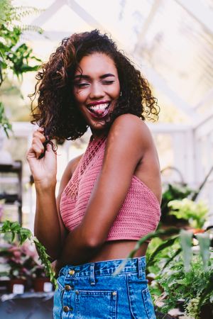 Young woman standing in a greenhouse playfully sticking out her tongue