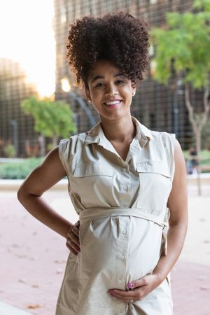 Smiling Black woman touching pregnant tummy