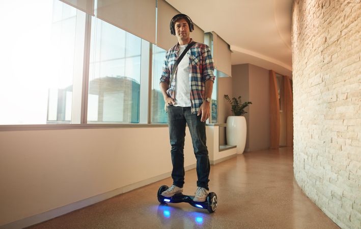 Male computer programmer leaving work on hoverboard