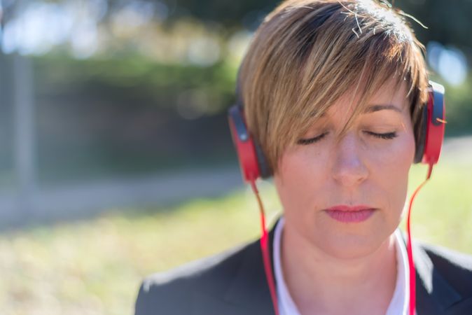 Woman listening to music on red headphones with eyes closed