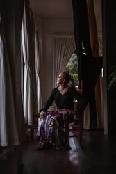 Woman dancer in suit for flamenco sitting and looking out window
