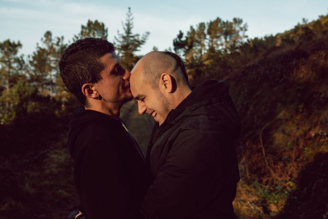Smiling men hugging and kissing on countryside road