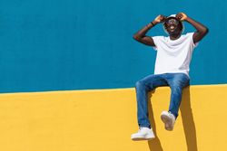 Happy man sitting on colorful wall